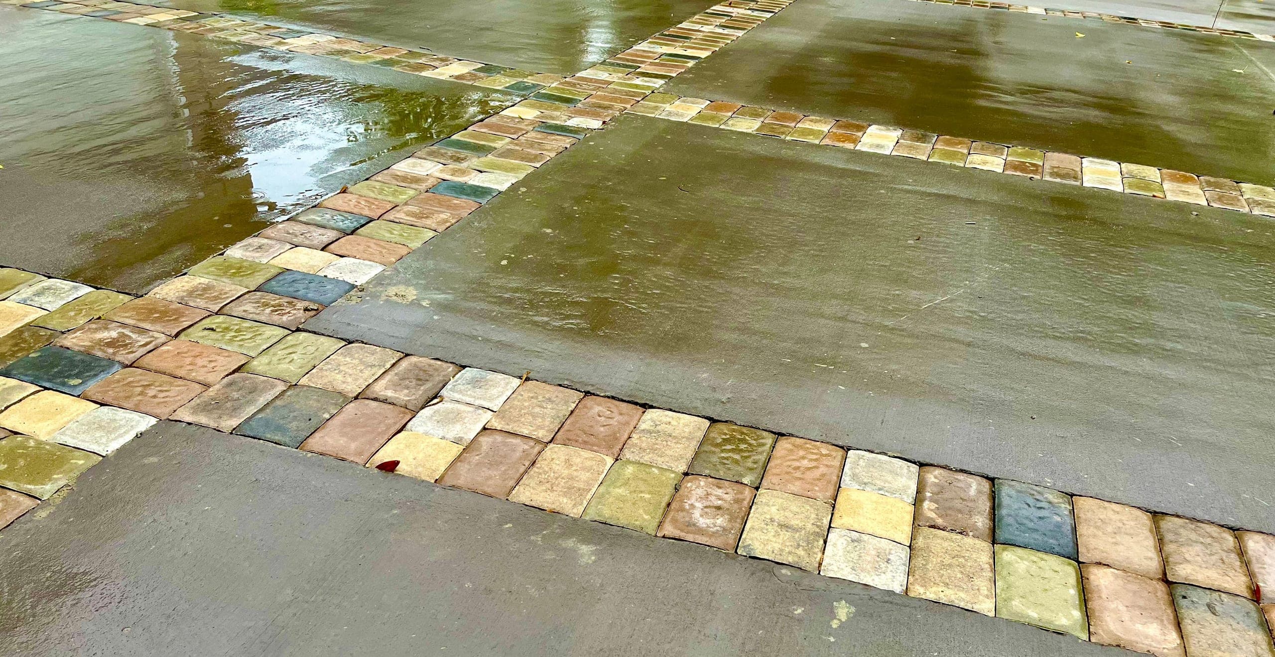 Paver bands cross a wet banded concrete drive.