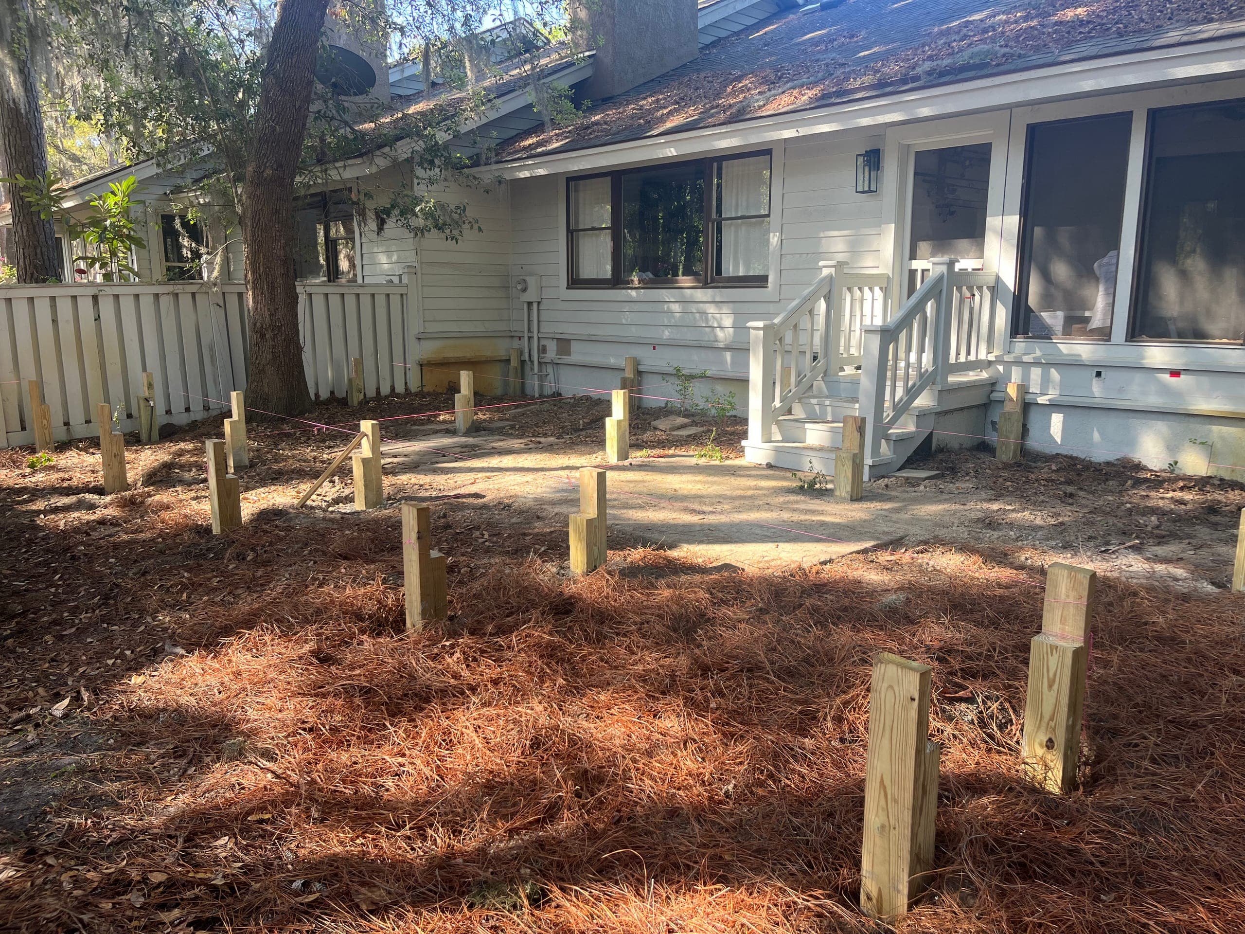 Deck footing posts set to grade with string lines across the yard.