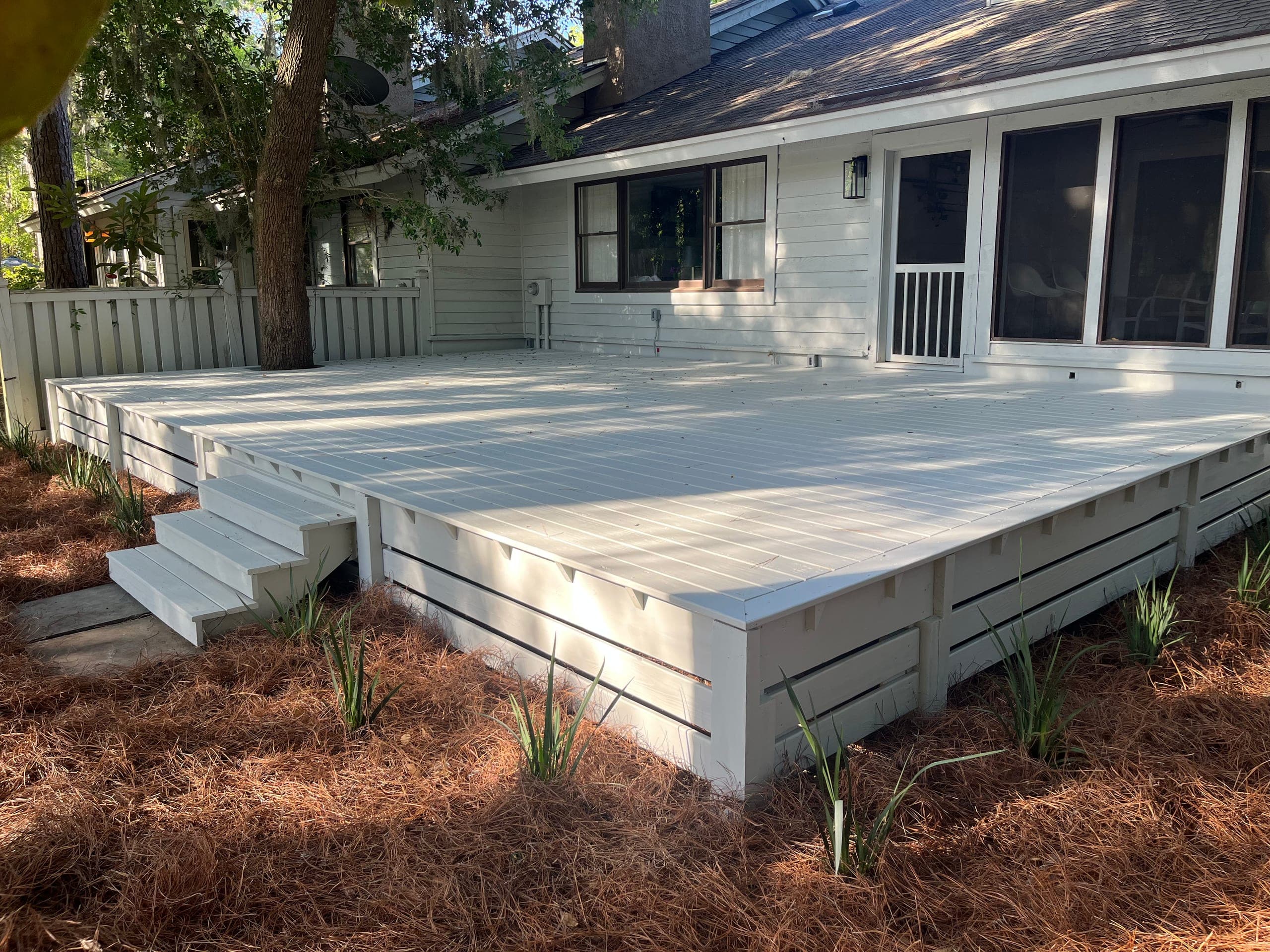The finished deck painted white to match the house, with slat skirting and corner steps.